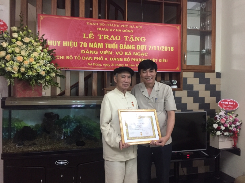 Ông Nguyễn Văn Trường - Phó Bí thư Thường trực Quận uỷ Hà Đông trao tặng huy hiệu 70 năm tuổi Đảng cho  Cụ Vũ Bá Ngạc